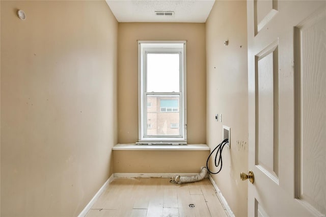 laundry area featuring washer hookup, hookup for an electric dryer, light hardwood / wood-style floors, and a textured ceiling