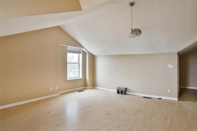 additional living space featuring lofted ceiling, a textured ceiling, and light wood-type flooring