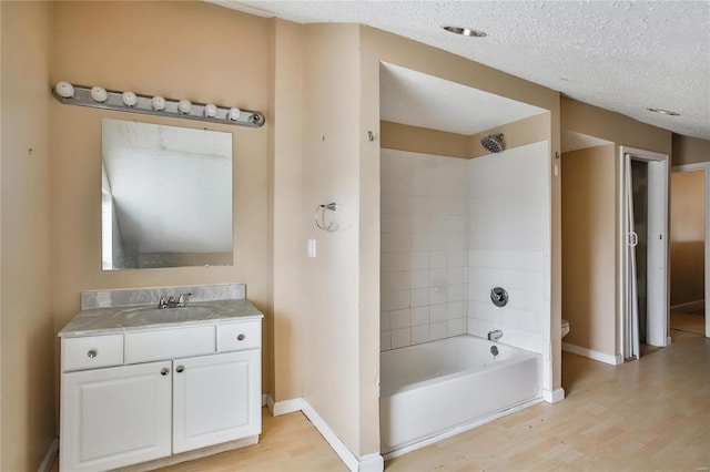 full bathroom featuring hardwood / wood-style flooring, bathing tub / shower combination, vanity, and a textured ceiling