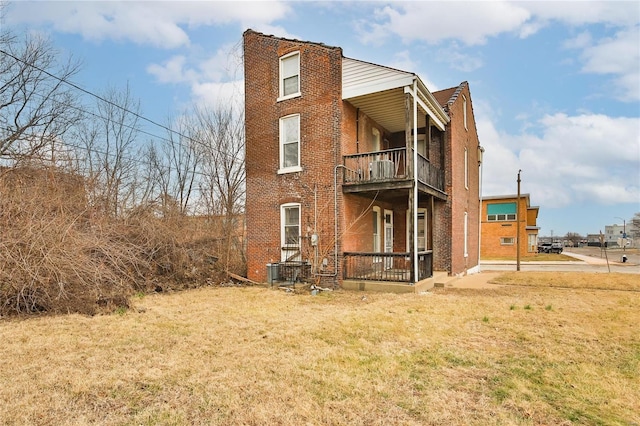 back of house featuring a balcony and a yard