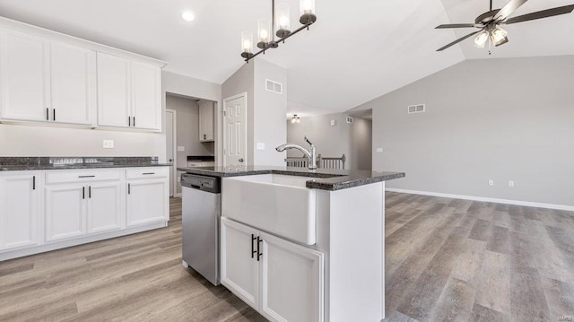 kitchen featuring a center island with sink, lofted ceiling, stainless steel dishwasher, and white cabinets