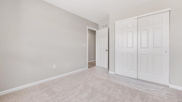 unfurnished bedroom featuring light colored carpet and a closet