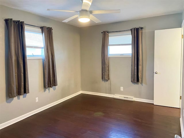 empty room with a ceiling fan, plenty of natural light, visible vents, and wood finished floors