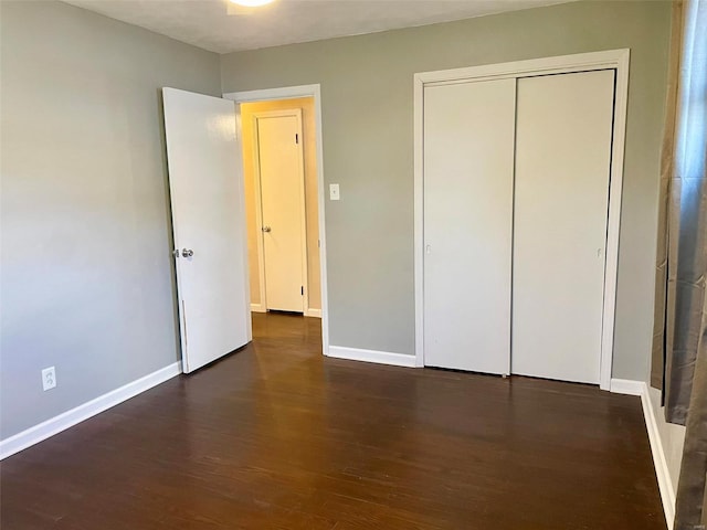 unfurnished bedroom with a closet, baseboards, and wood finished floors