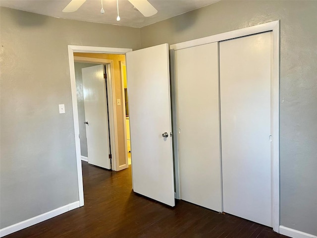 unfurnished bedroom featuring dark wood-style floors, a closet, ceiling fan, and baseboards