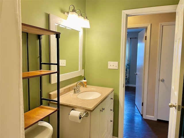 half bathroom with baseboards, wood finished floors, and vanity