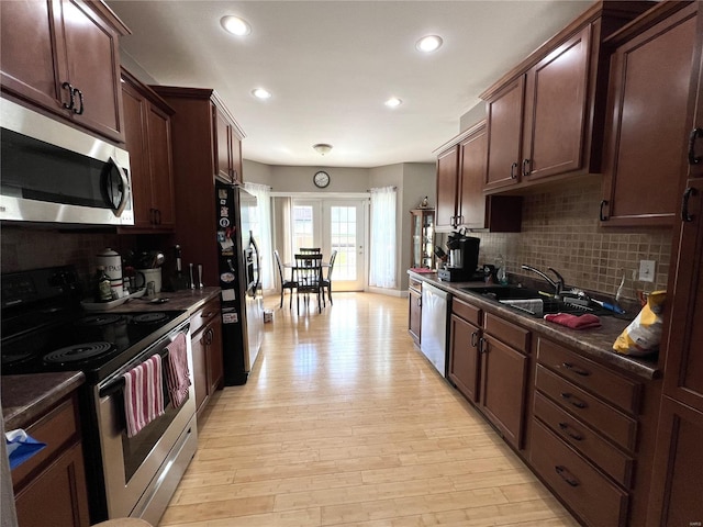 kitchen featuring decorative backsplash, stainless steel appliances, sink, and light hardwood / wood-style flooring