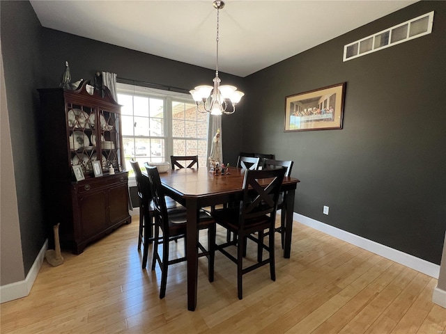 dining area with a notable chandelier and light hardwood / wood-style floors