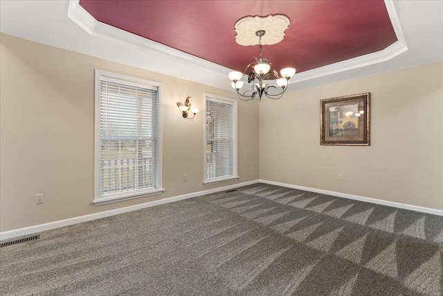 carpeted spare room featuring a raised ceiling, crown molding, and a notable chandelier