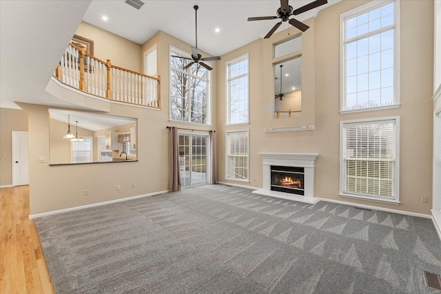 unfurnished living room featuring hardwood / wood-style flooring, ceiling fan, and a high ceiling