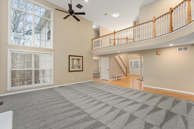 unfurnished living room featuring a high ceiling, hardwood / wood-style floors, and ceiling fan