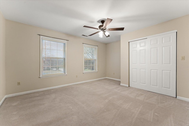 unfurnished bedroom featuring ceiling fan, light colored carpet, and a closet