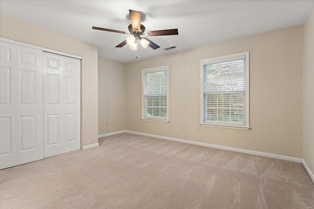 unfurnished bedroom featuring light carpet, ceiling fan, and a closet