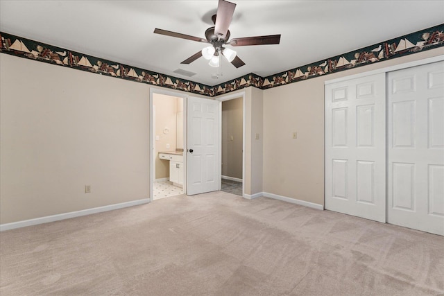 unfurnished bedroom with ceiling fan, a closet, connected bathroom, and light carpet