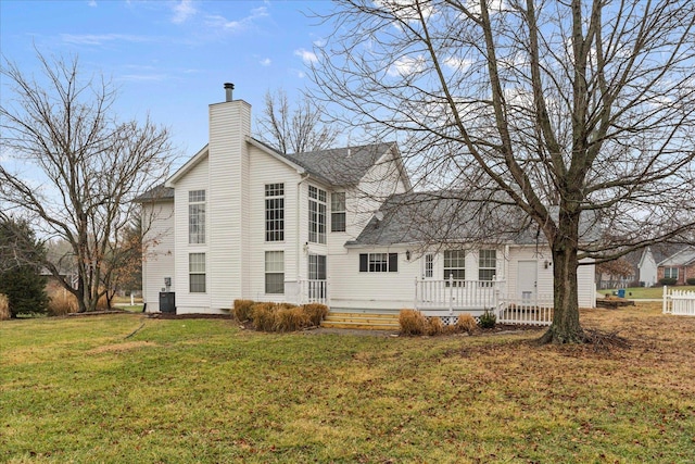 rear view of house featuring central AC and a lawn