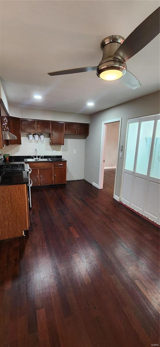 kitchen featuring gas range, dark hardwood / wood-style floors, and ceiling fan