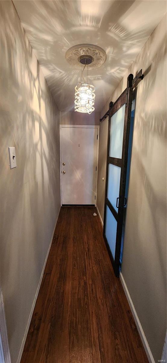 hallway with dark wood-type flooring and a barn door