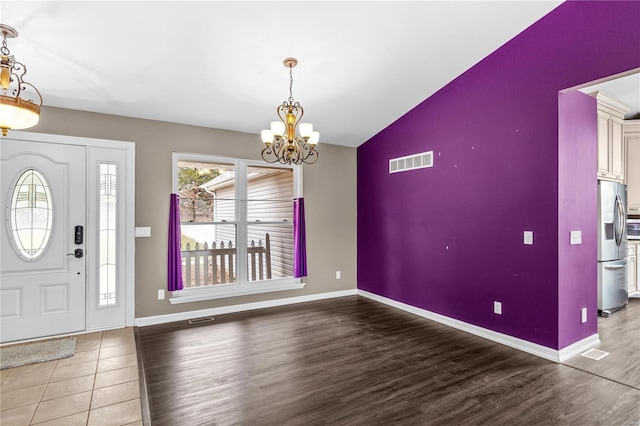 entryway with hardwood / wood-style floors and a notable chandelier