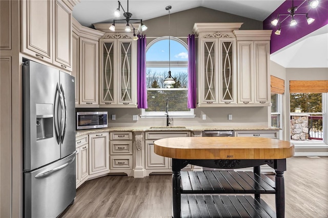 kitchen featuring pendant lighting, sink, stainless steel appliances, and cream cabinetry