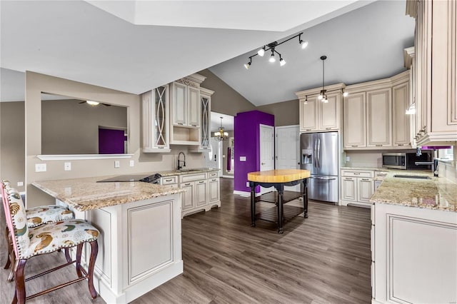 kitchen with sink, stainless steel appliances, light stone countertops, decorative light fixtures, and kitchen peninsula