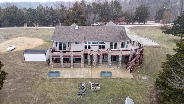 rear view of house featuring a patio area, a lawn, a deck, and a storage unit