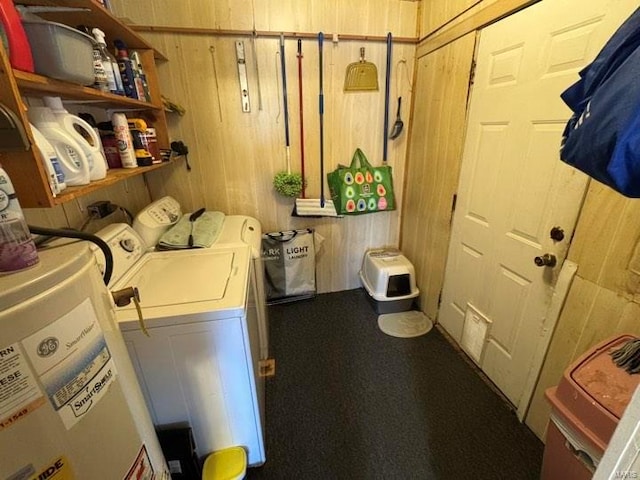 laundry area with independent washer and dryer, gas water heater, and wood walls