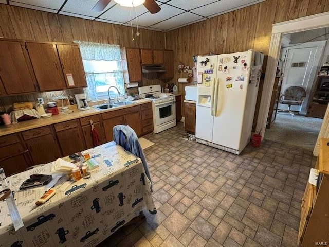 kitchen featuring white appliances, a paneled ceiling, sink, and wood walls