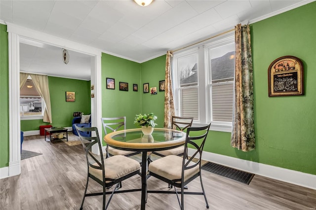 dining area with ornamental molding and wood-type flooring