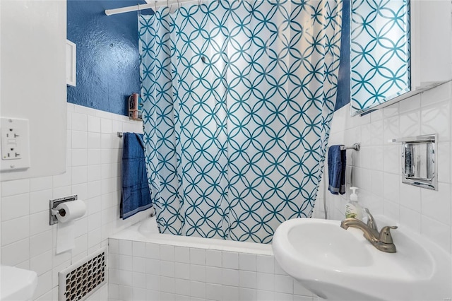 full bathroom featuring radiator heating unit, sink, tile walls, shower / bath combination with curtain, and toilet