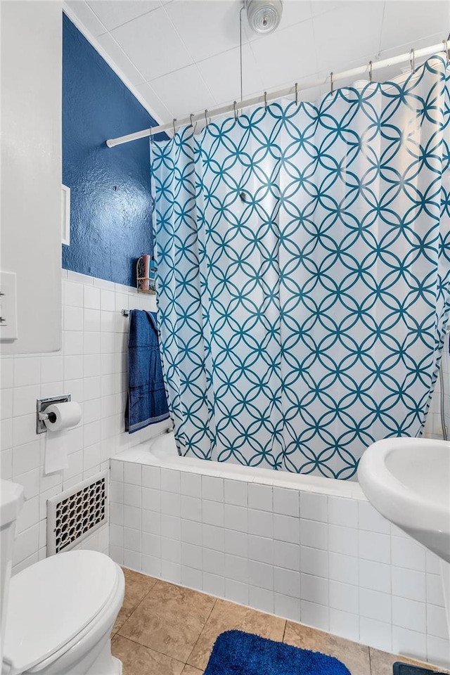 bathroom featuring shower / tub combo with curtain, radiator, tile walls, tile patterned floors, and toilet