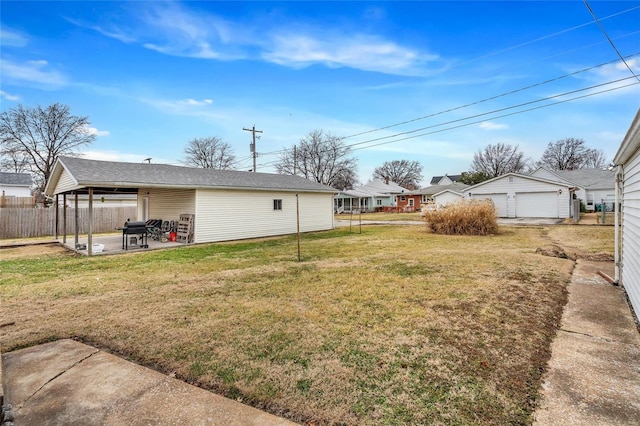 view of yard featuring a garage, a patio, and an outdoor structure