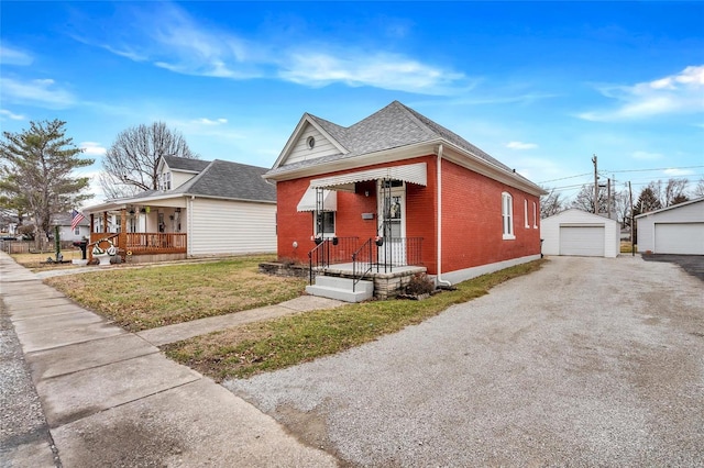 bungalow-style home with a garage, an outbuilding, covered porch, and a front lawn