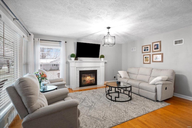 living room featuring hardwood / wood-style flooring, a notable chandelier, and a textured ceiling