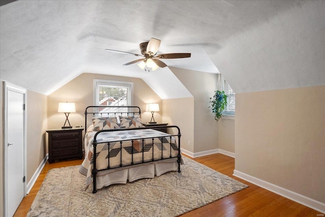 bedroom featuring ceiling fan, vaulted ceiling, a textured ceiling, and light wood-type flooring