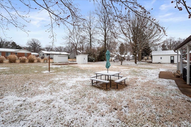 snowy yard featuring a storage unit