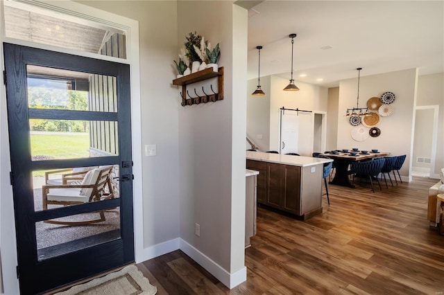 interior space with pendant lighting, dark wood-type flooring, a barn door, and a center island