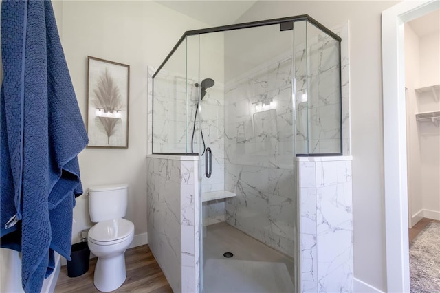 bathroom with hardwood / wood-style flooring, a shower with shower door, and toilet