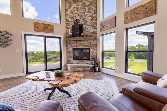 living room with a towering ceiling, a fireplace, and hardwood / wood-style floors