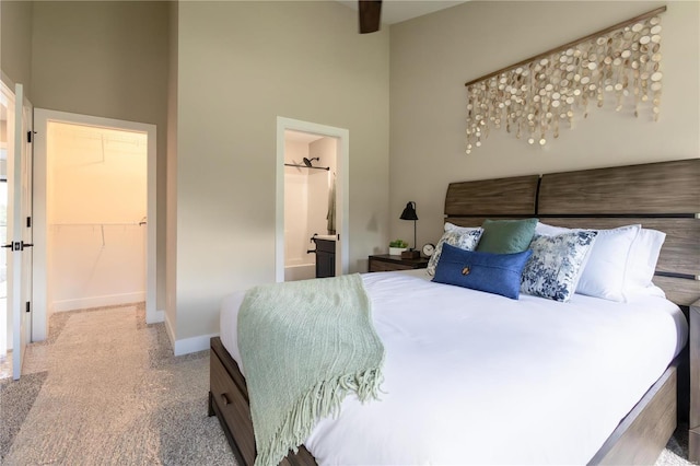 carpeted bedroom with a towering ceiling, a spacious closet, and ensuite bath