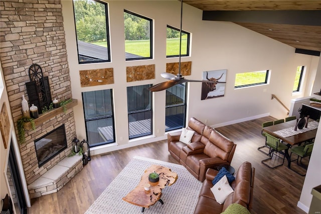 living room featuring plenty of natural light, a stone fireplace, dark hardwood / wood-style flooring, and high vaulted ceiling