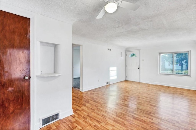 unfurnished living room featuring plenty of natural light, a textured ceiling, and light wood-type flooring