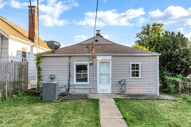 rear view of property featuring central AC and a lawn