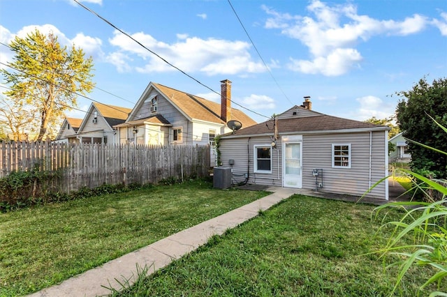 back of house featuring central AC and a lawn