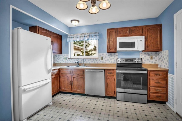 kitchen with stainless steel appliances, a chandelier, sink, and backsplash