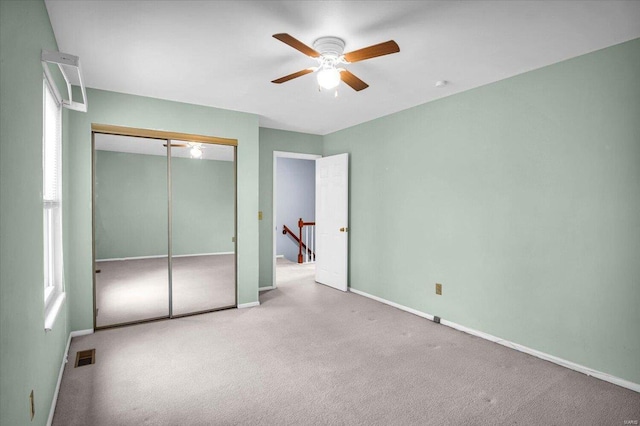 unfurnished bedroom with light carpet, a closet, and ceiling fan