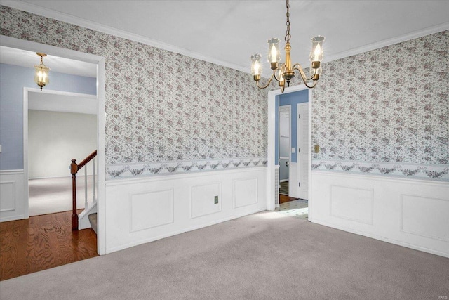 carpeted empty room featuring an inviting chandelier and ornamental molding