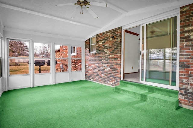 unfurnished sunroom featuring a healthy amount of sunlight, vaulted ceiling with beams, and ceiling fan