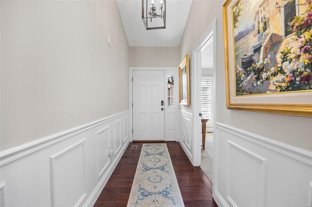 doorway featuring dark wood-type flooring and a chandelier