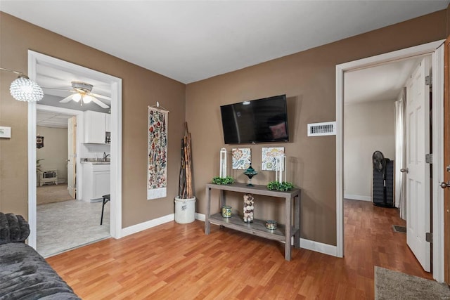 living room featuring ceiling fan, wood-type flooring, and sink