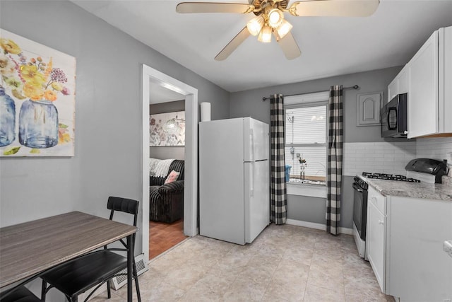 kitchen featuring tasteful backsplash, white cabinets, white fridge, light stone counters, and gas stove